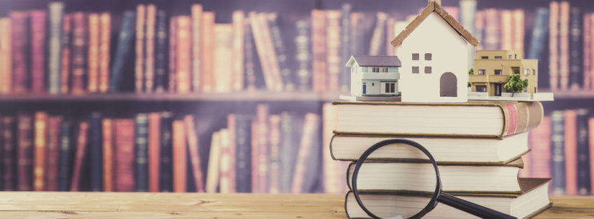 pile of books with a house sat on top