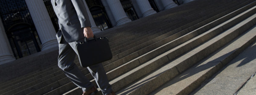 man holding briefcase in front of law courts