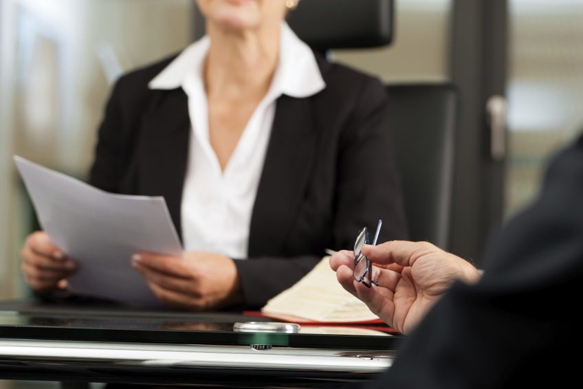 man speaking to lawyer while she holds papers