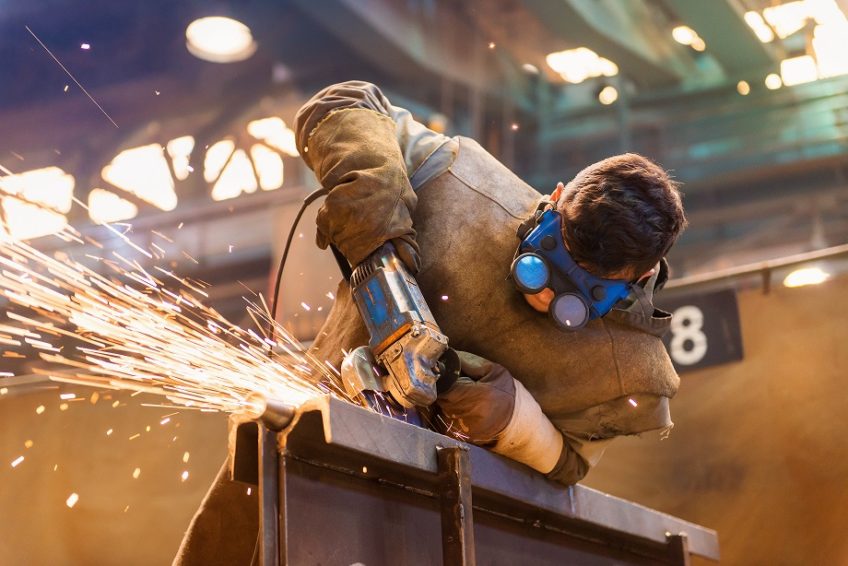 Engineer cutting metal with sparks flying