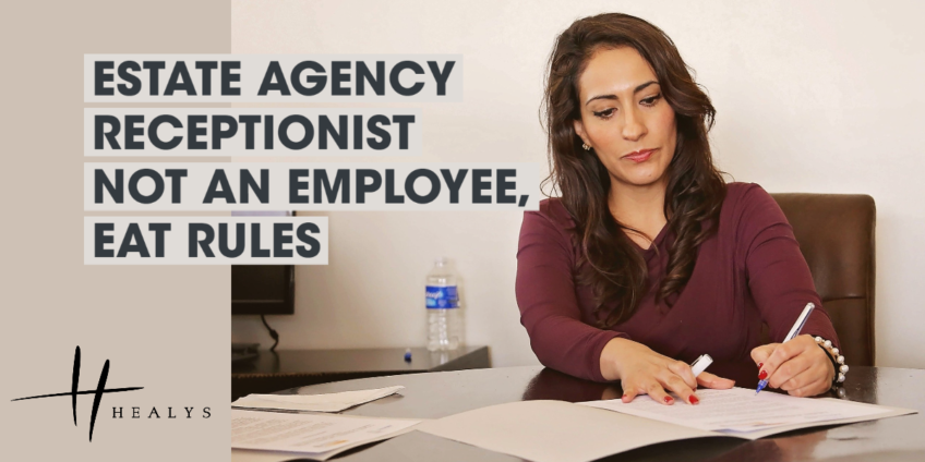 Female receptionist working at desk, writing on papers