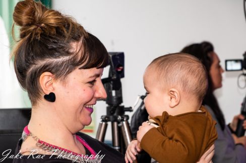 image of attendee smiling while holding her baby