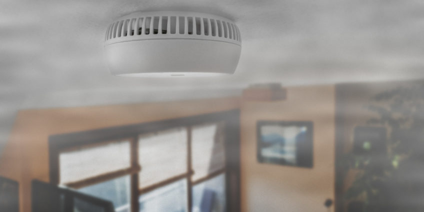 Close up of a smoke alarm in a smoke filled room