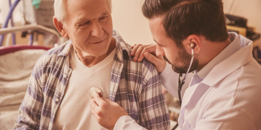 Doctor is listening to the heartbeat of an old man using a stethoscope