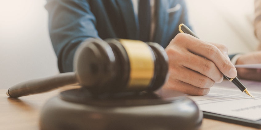 Close up of judges hammer while judge signs papers