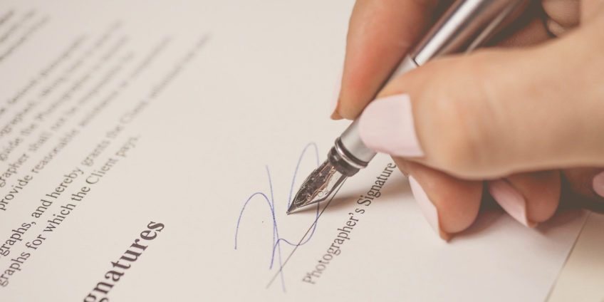 Womans hand signing contract