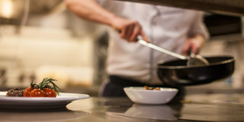 Male chef in high class kitchen plating food