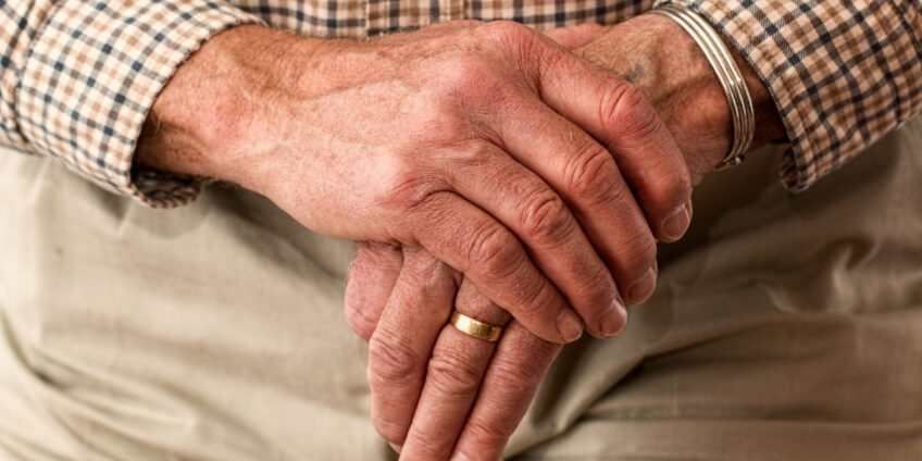 elderly man holding his hands together