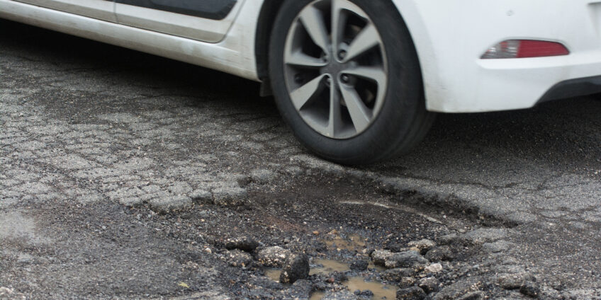 car driving over a pothole