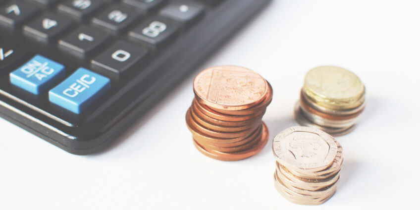 accounting calculator next to piles of pennies and pounds