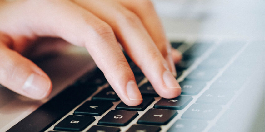 close up of hand typing on laptop keyboard